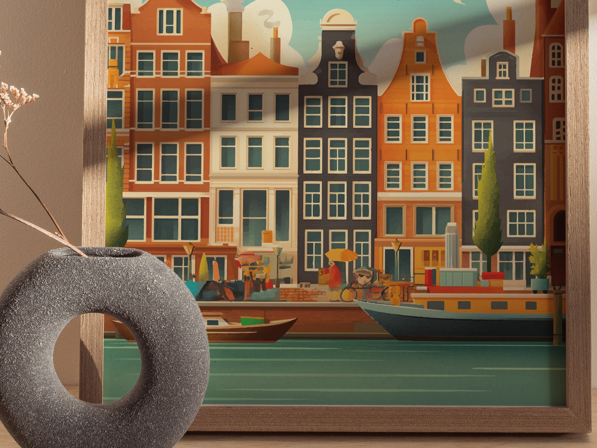A framed artwork of Amsterdams colorful canal-side buildings is displayed beside a textured circular vase with dried grasses, creating a harmonious decorative setting.