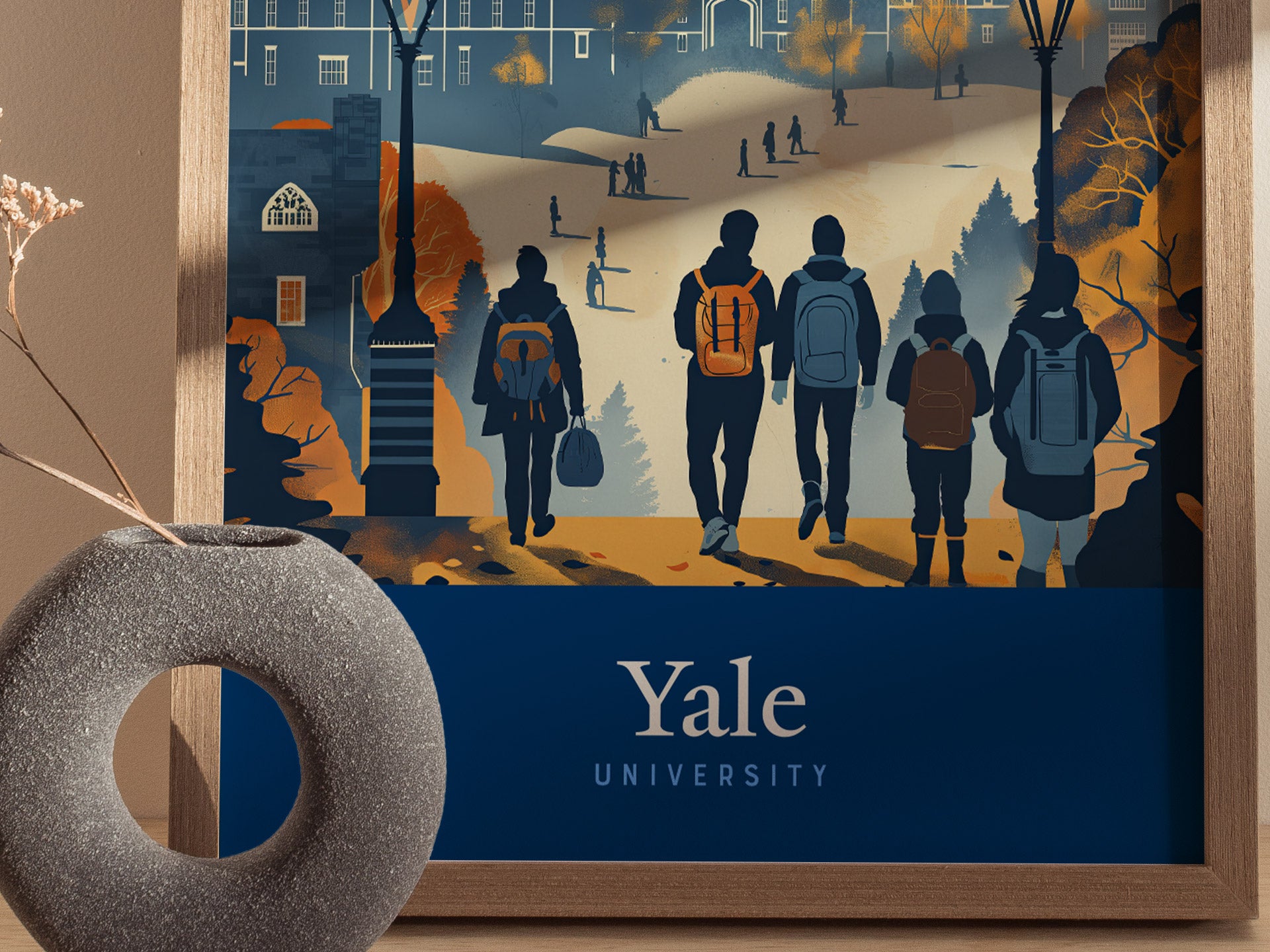 A framed poster featuring silhouettes of five people walking towards a grand building on a campus, with Yale University text below. A decorative vase is visible in the foreground.