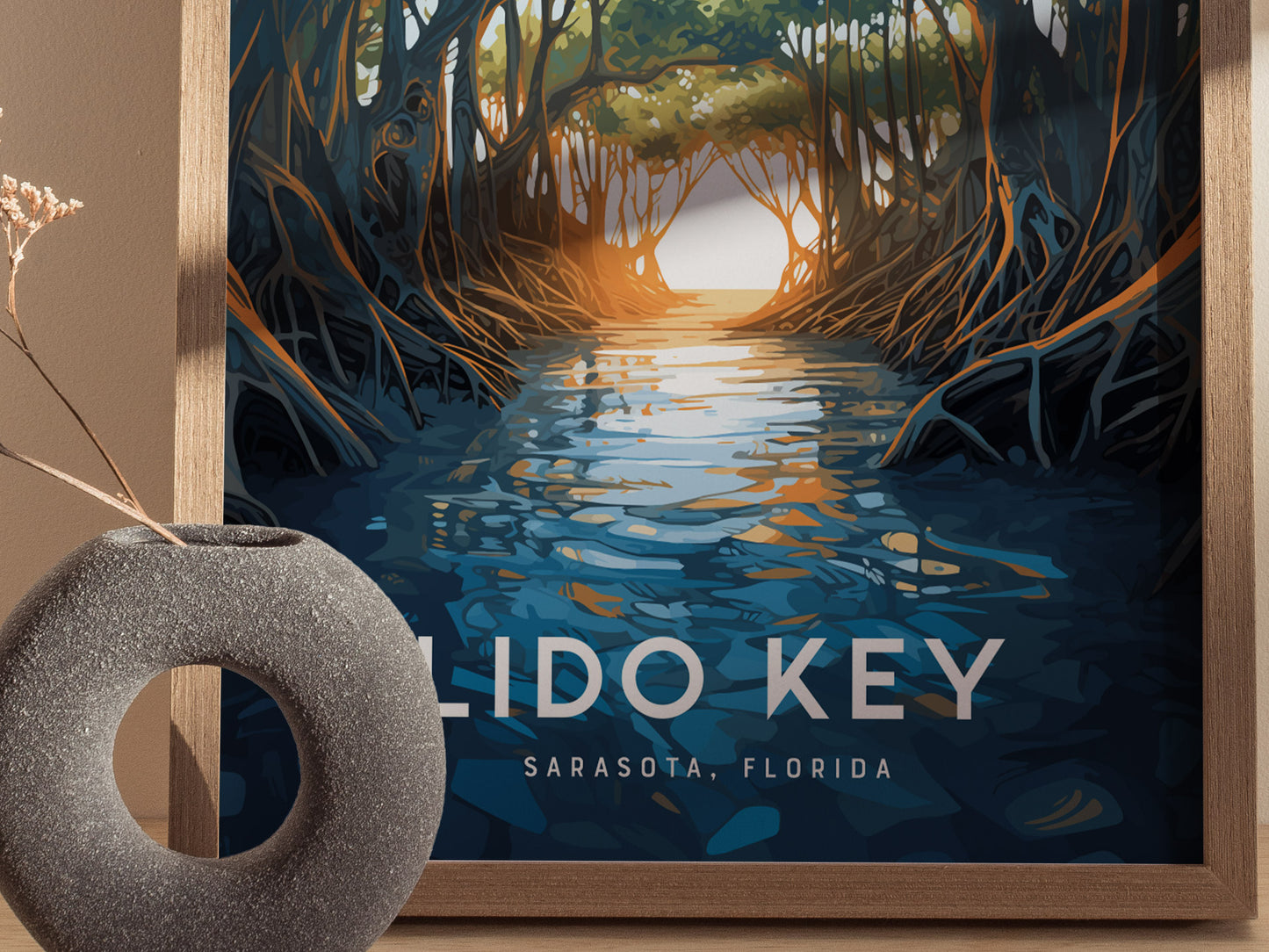 A framed poster of Lido Key, Sarasota, Florida, depicts a tranquil waterway surrounded by arching mangrove trees. A textured gray vase with dried flowers sits in the foreground.