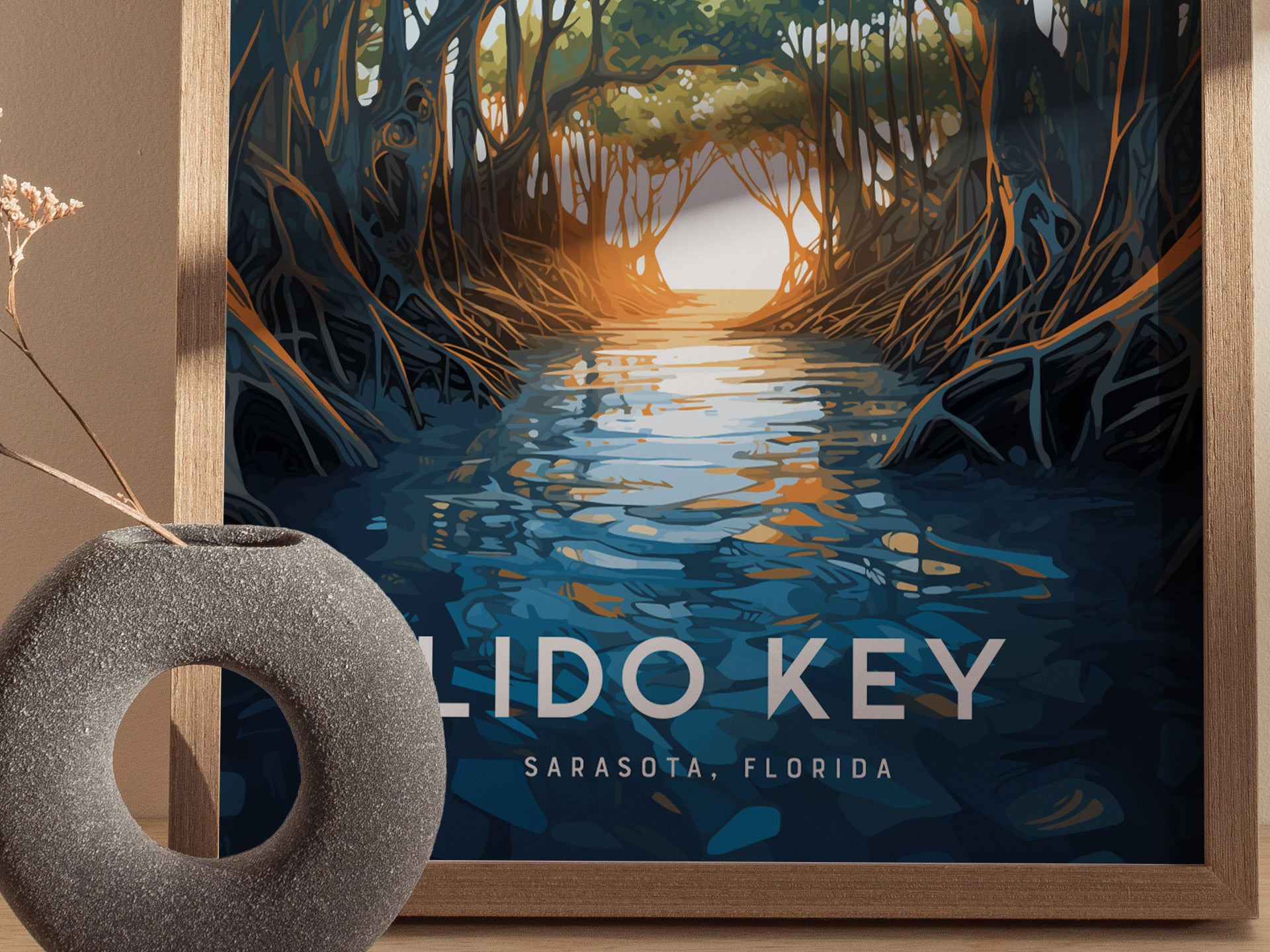 A framed poster of Lido Key, Sarasota, Florida, depicts a tranquil waterway surrounded by arching mangrove trees. A textured gray vase with dried flowers sits in the foreground.