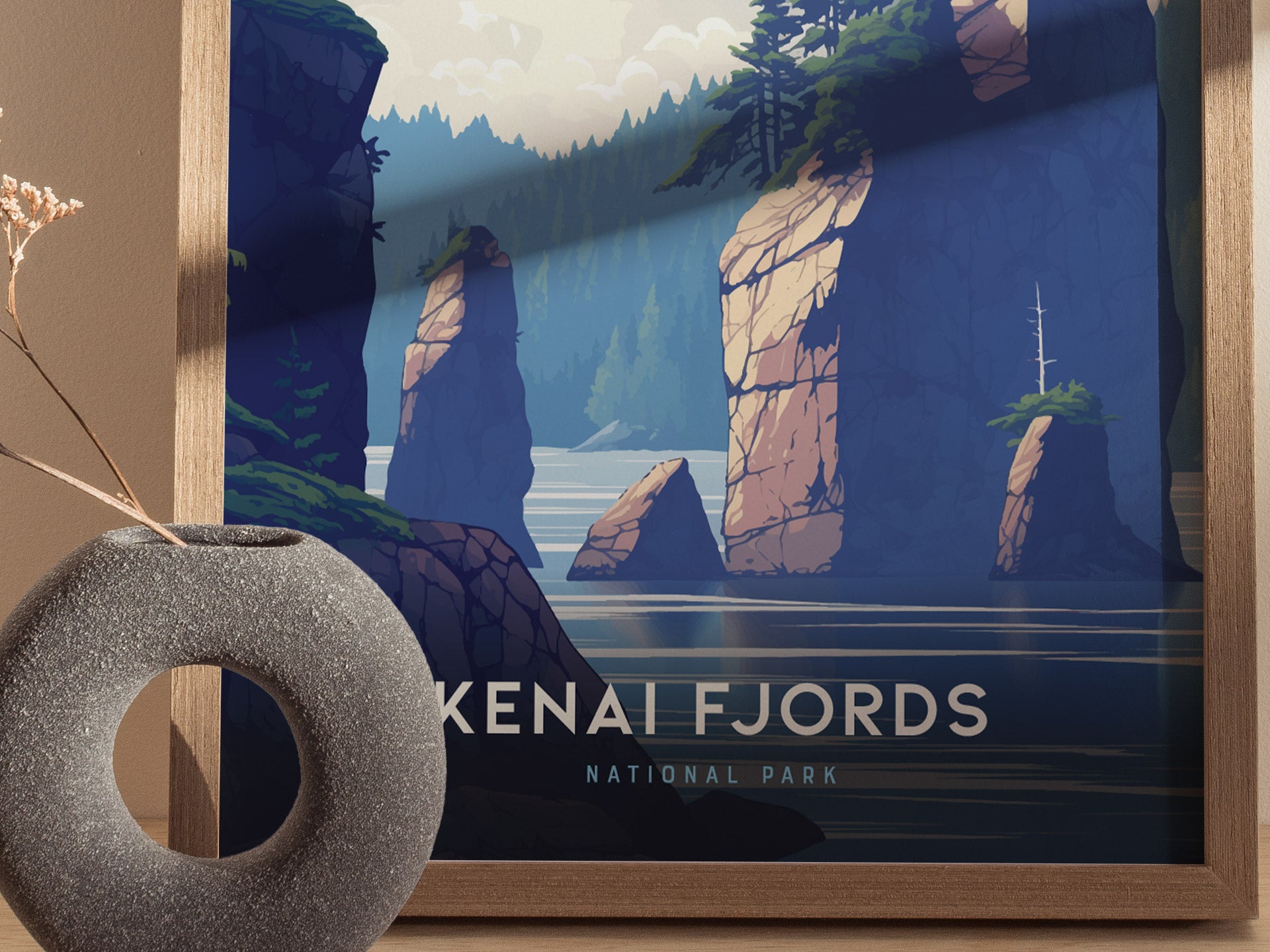 A framed poster of Kenai Fjords National Park features stylized rocky cliffs and a calm fjord, with a minimalist gray vase in the foreground.