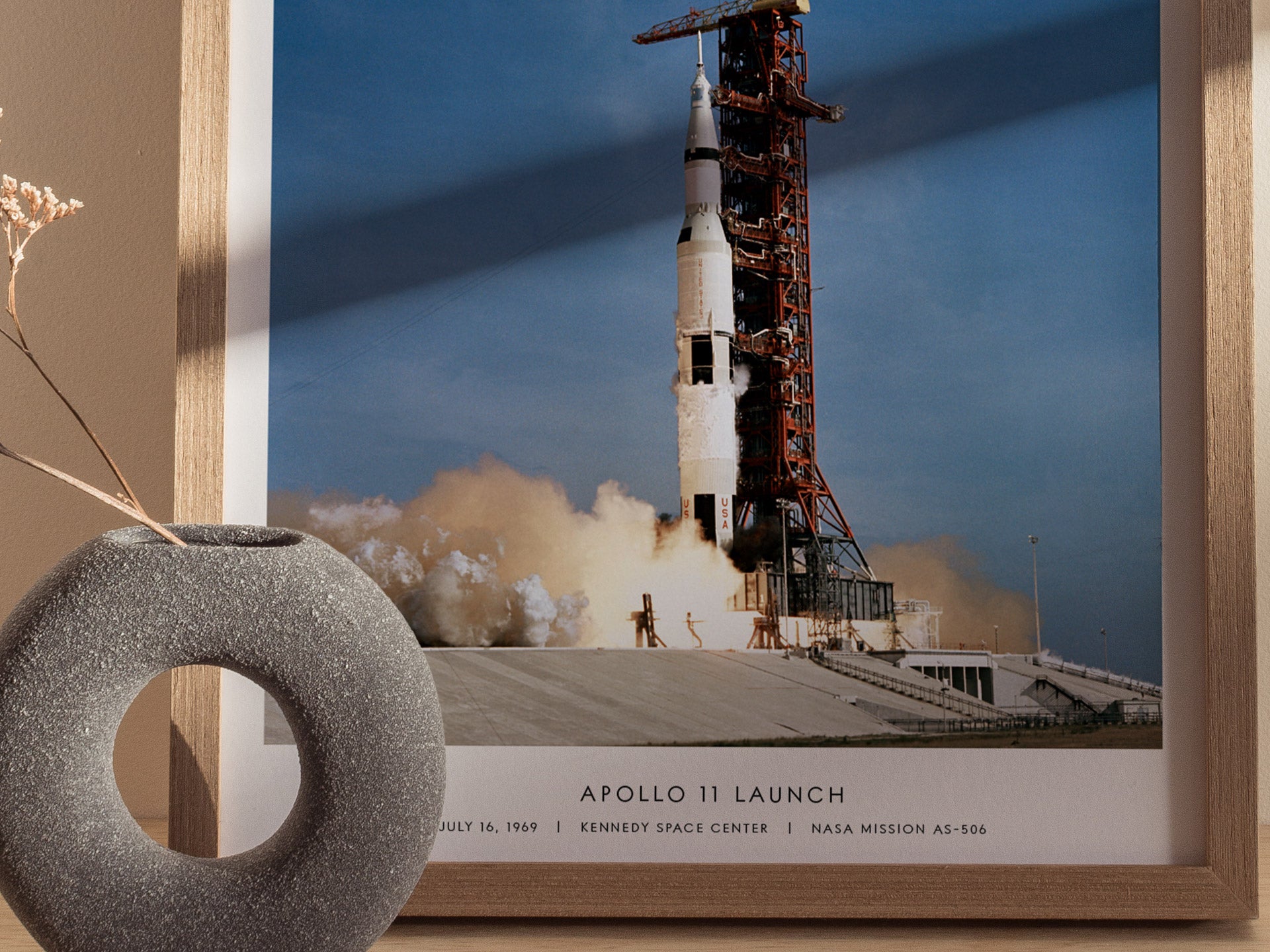 Framed photograph of Apollo 11 launch with a decorative object in the foreground.