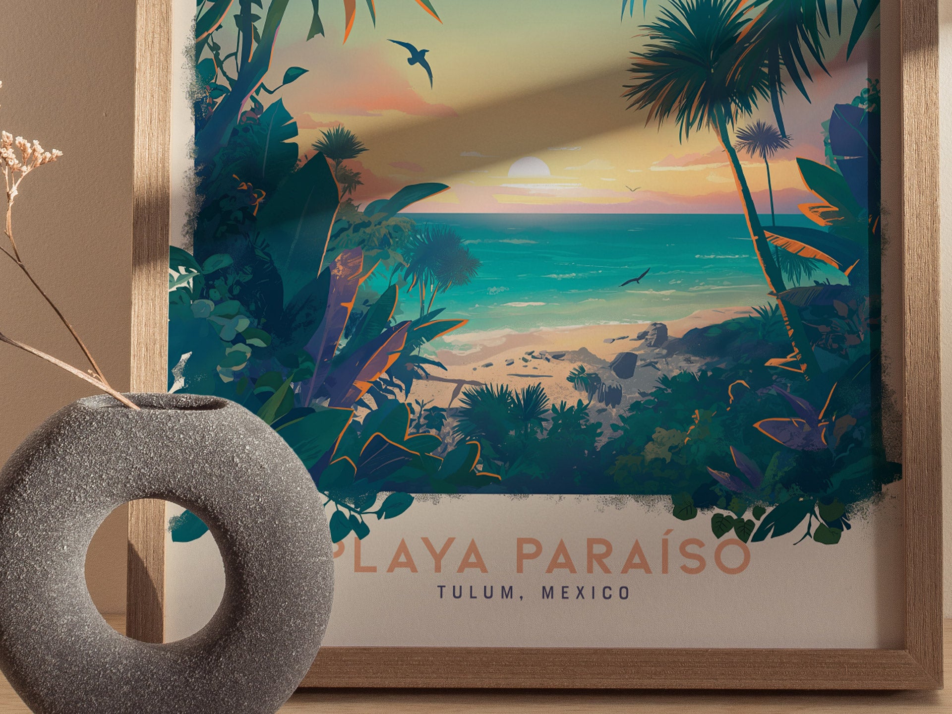 A framed poster depicts a vibrant tropical beach scene with lush greenery, a sunset over turquoise waters, and birds in flight. A round, textured vase with dried flowers sits nearby.