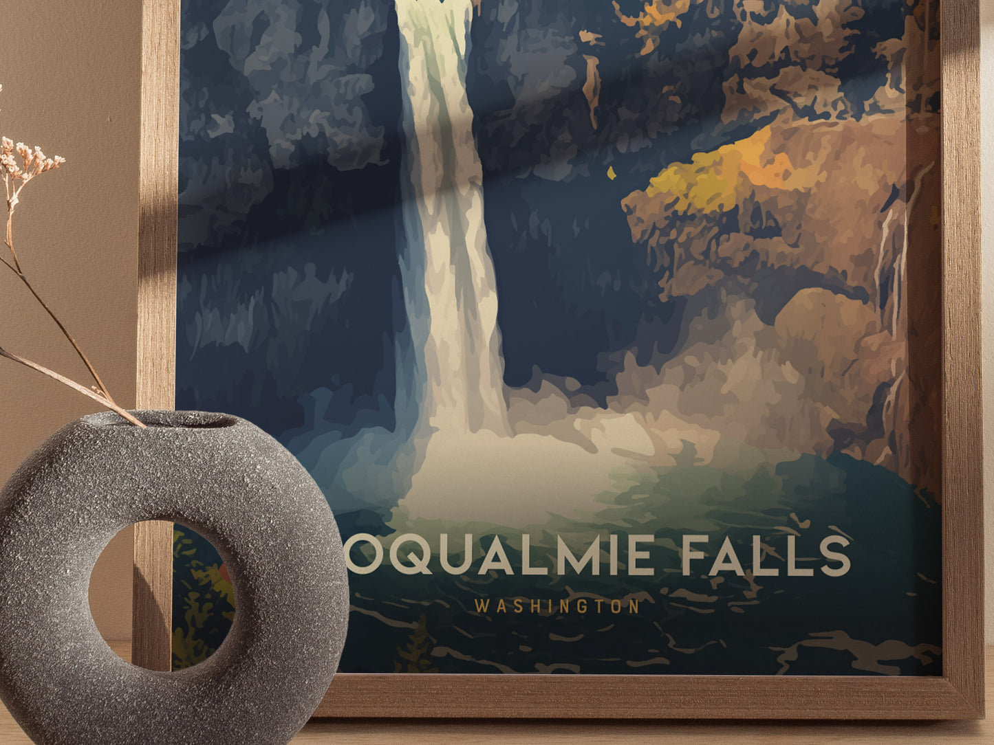 A framed poster of Snoqualmie Falls in Washington, featuring a stylized waterfall with bold colors. In the foreground, a textured circular vase holds a dried plant.