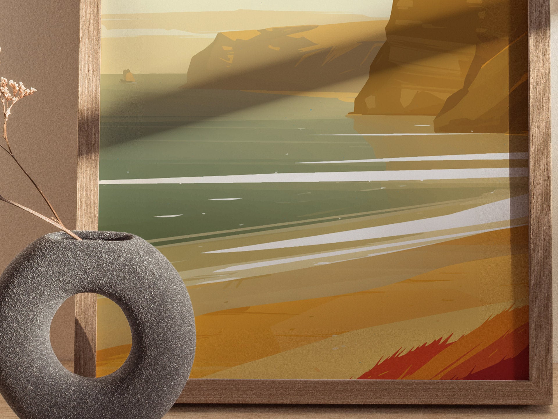 A framed poster shows an abstract depiction of a coastal landscape with golden cliffs and greenish waves. In the foreground, a circular stone vase holds a dried plant.