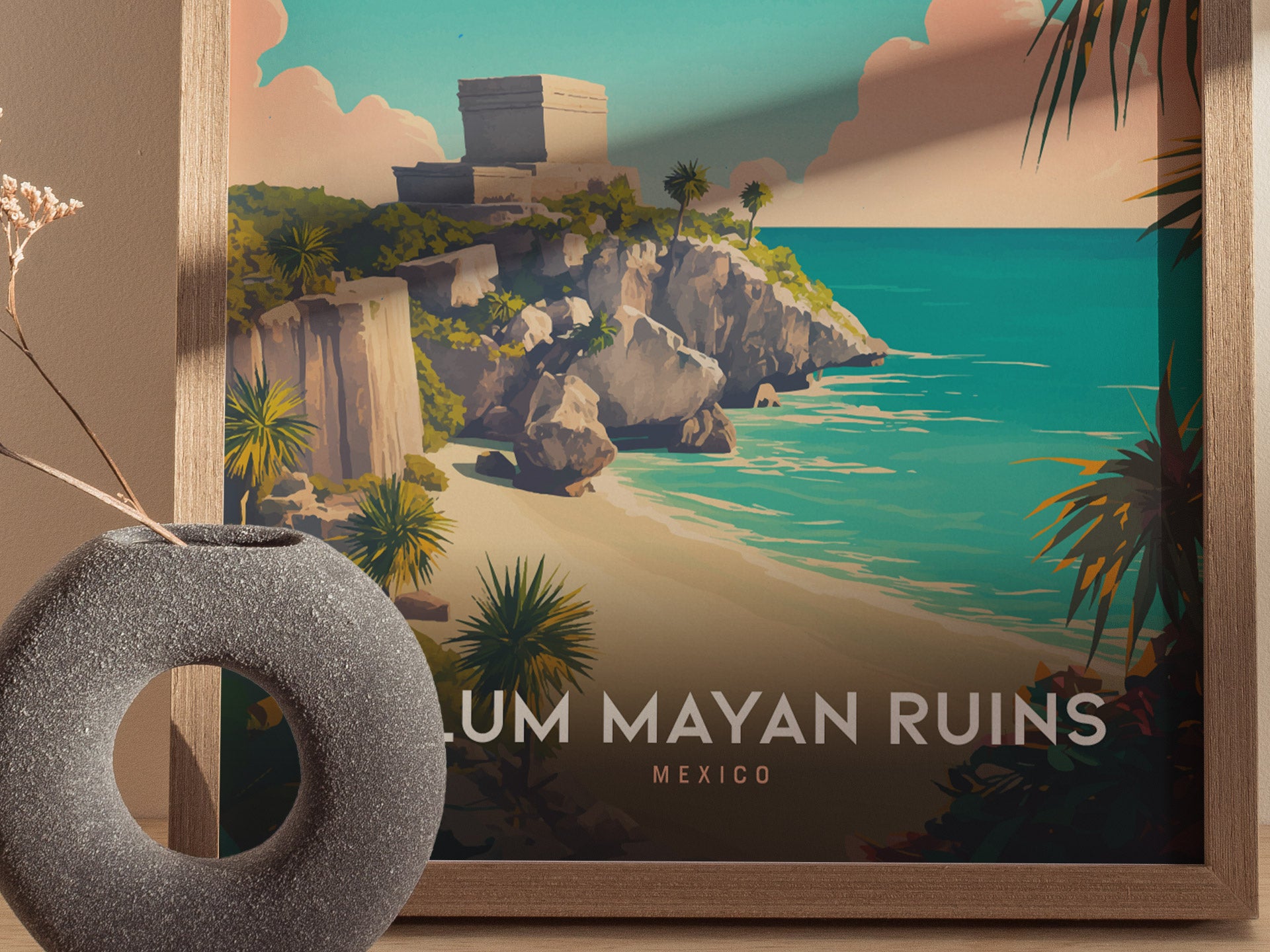A framed poster of Tulum Mayan Ruins features a dramatic cliffside view with turquoise waters and lush greenery. A round, textured vase sits nearby, adding a decorative element.