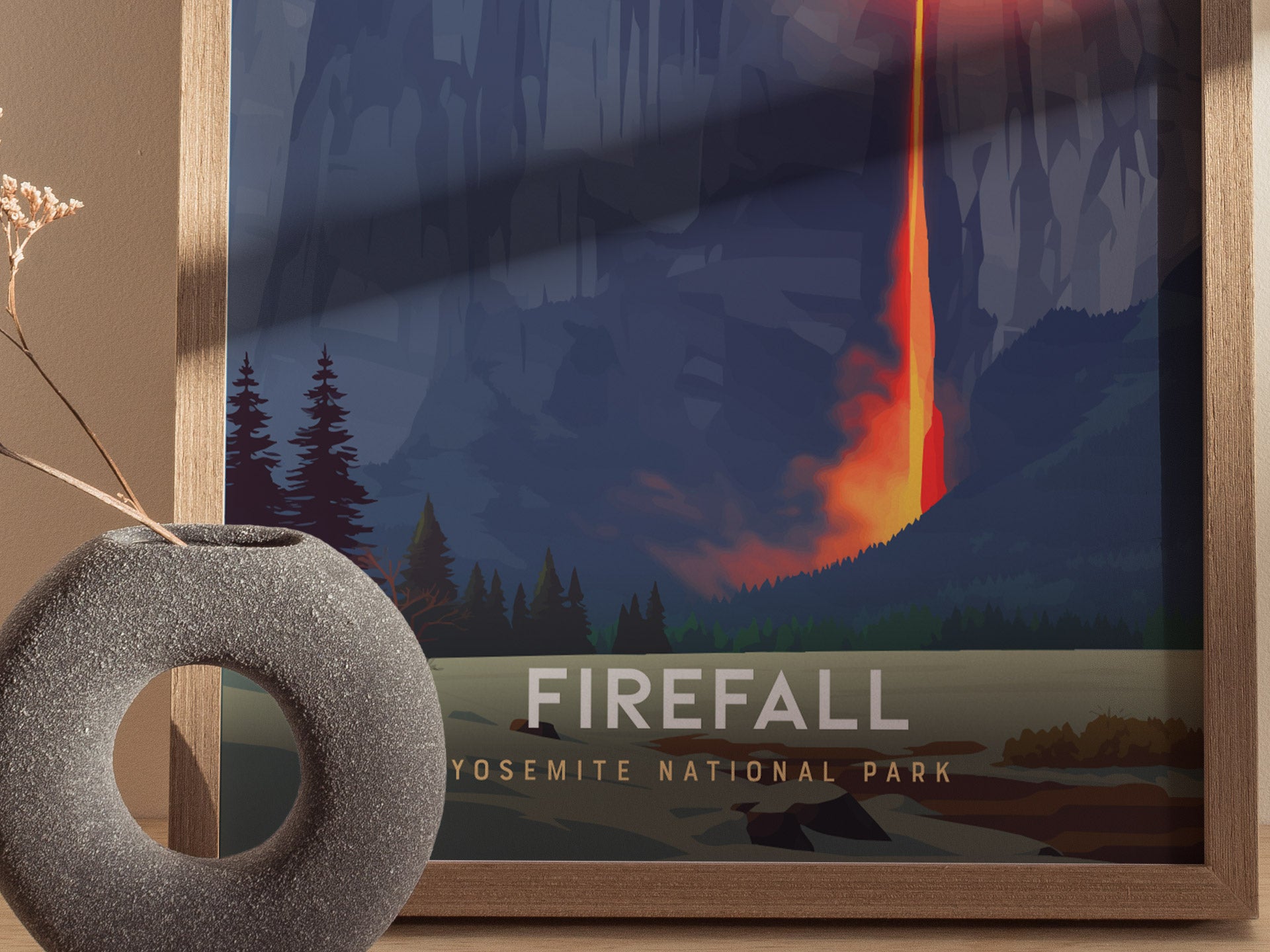 Framed artwork of a firefall in Yosemite National Park with a decorative stone object.