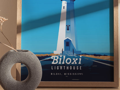 A framed poster depicts the Biloxi Lighthouse in a minimal vector style with a blue background. A textured gray vase with dried flowers is placed in the foreground.