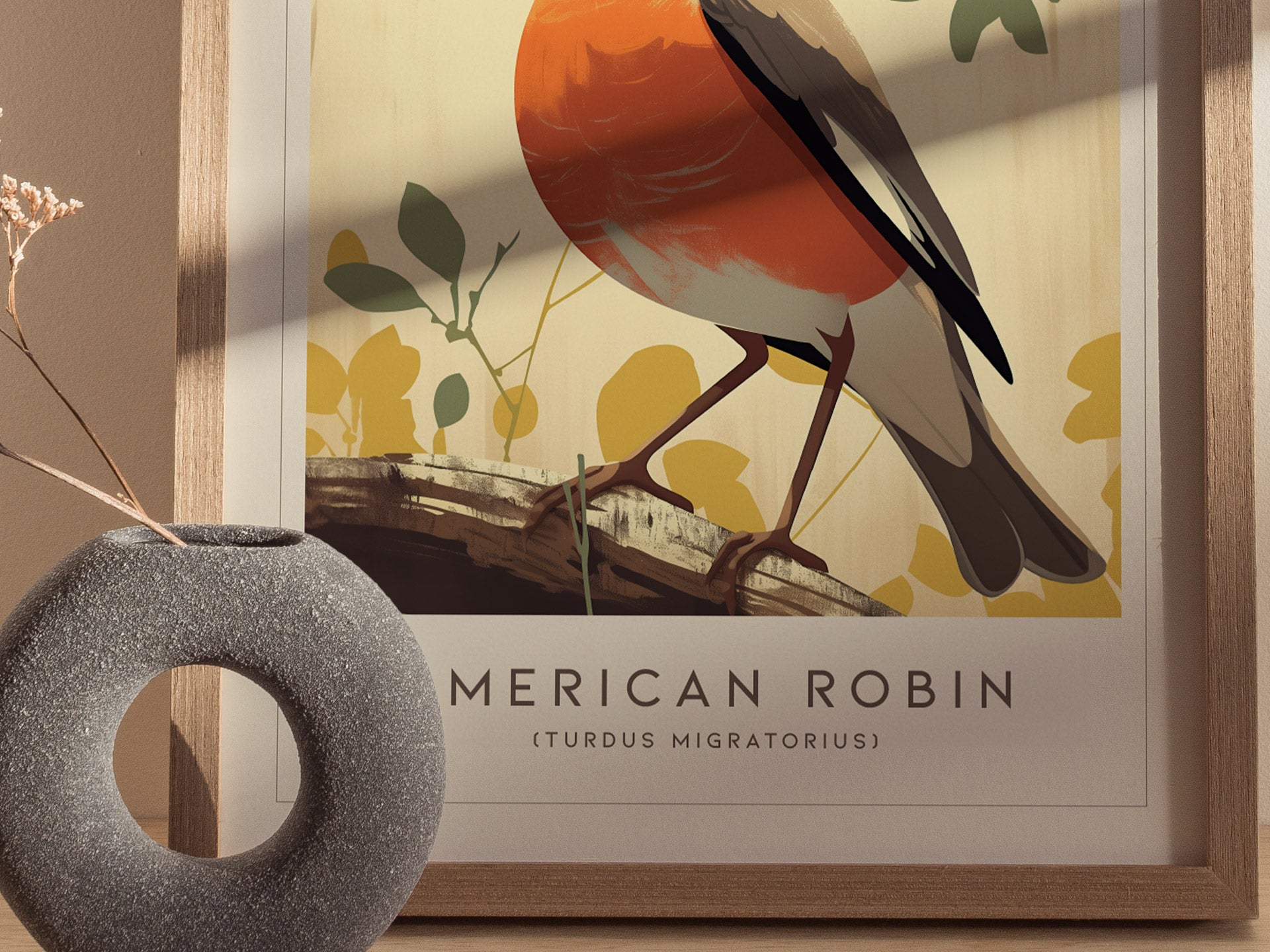 Framed poster of an American Robin with a red breast perched on a branch, surrounded by abstract yellow and green foliage. A textured, round gray vase sits in the foreground.