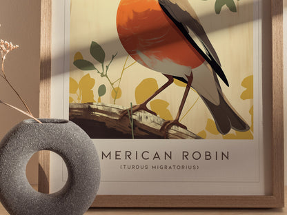 Framed poster of an American Robin with a red breast perched on a branch, surrounded by abstract yellow and green foliage. A textured, round gray vase sits in the foreground.