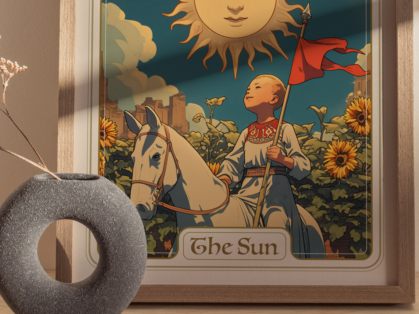 A framed tarot card poster features a child on a white horse with a red flag, surrounded by sunflowers and a smiling sun. A gray vase is in the foreground.
