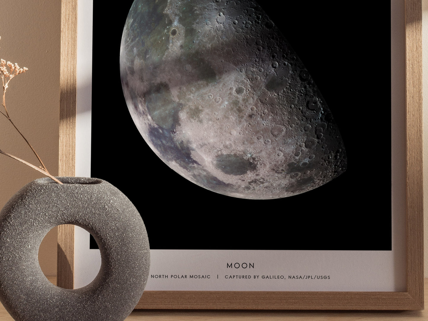 Framed print of the moon with a decorative object on a neutral background