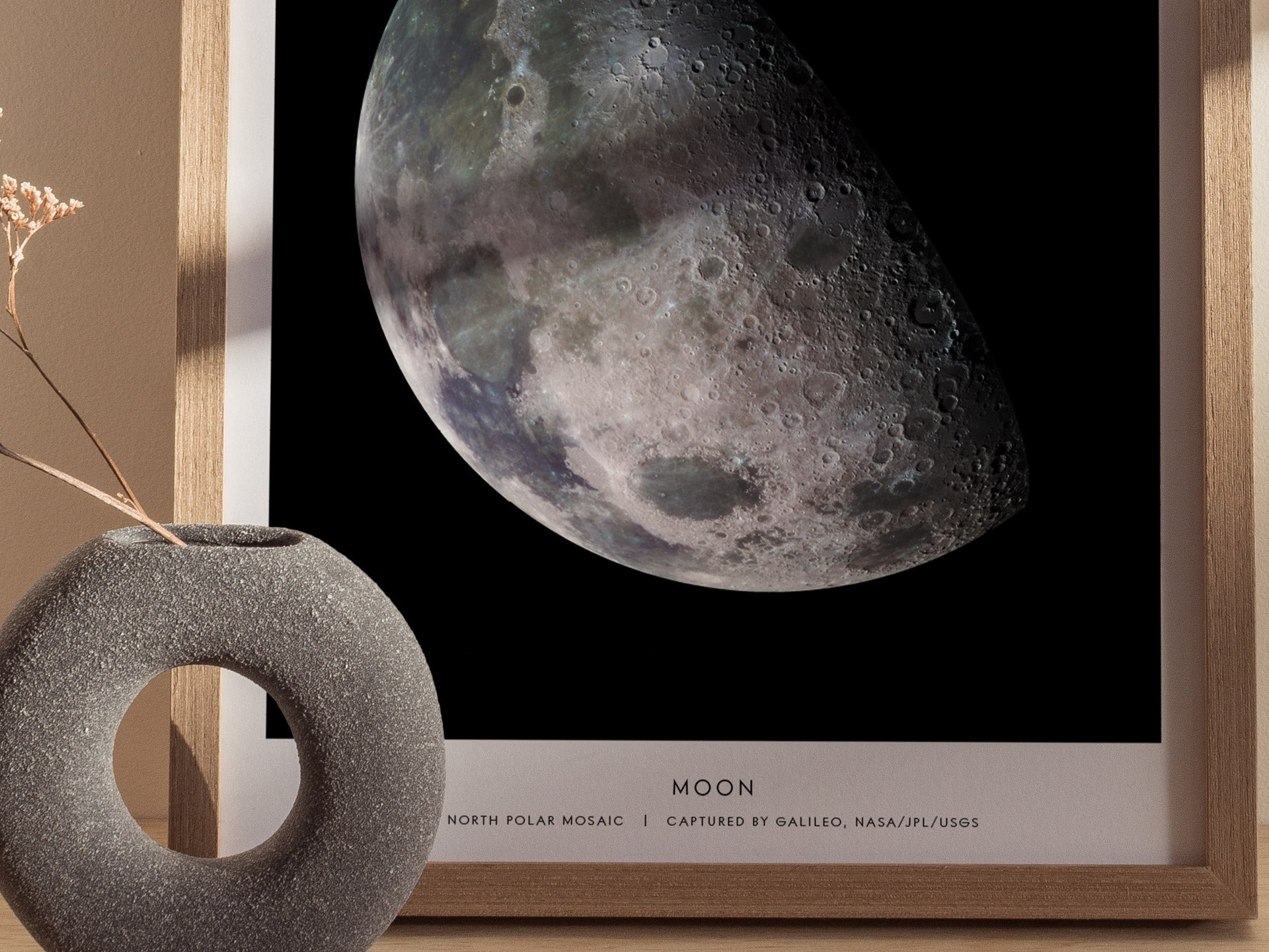Framed print of the moon with a decorative object on a neutral background