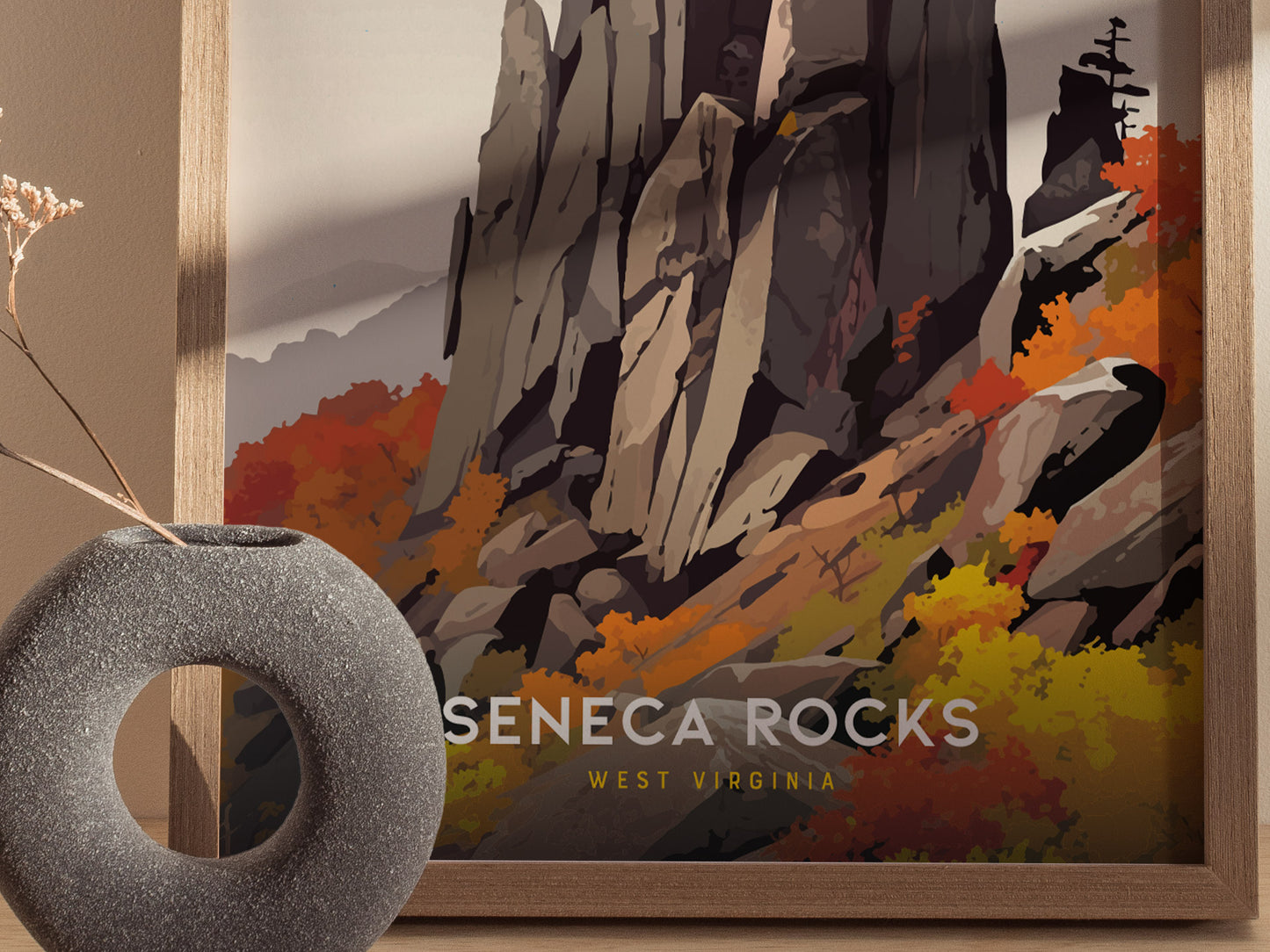 A framed poster of Seneca Rocks features the striking quartzite formation surrounded by vibrant autumn foliage. A textured, circular vase with dried flowers is in the foreground.