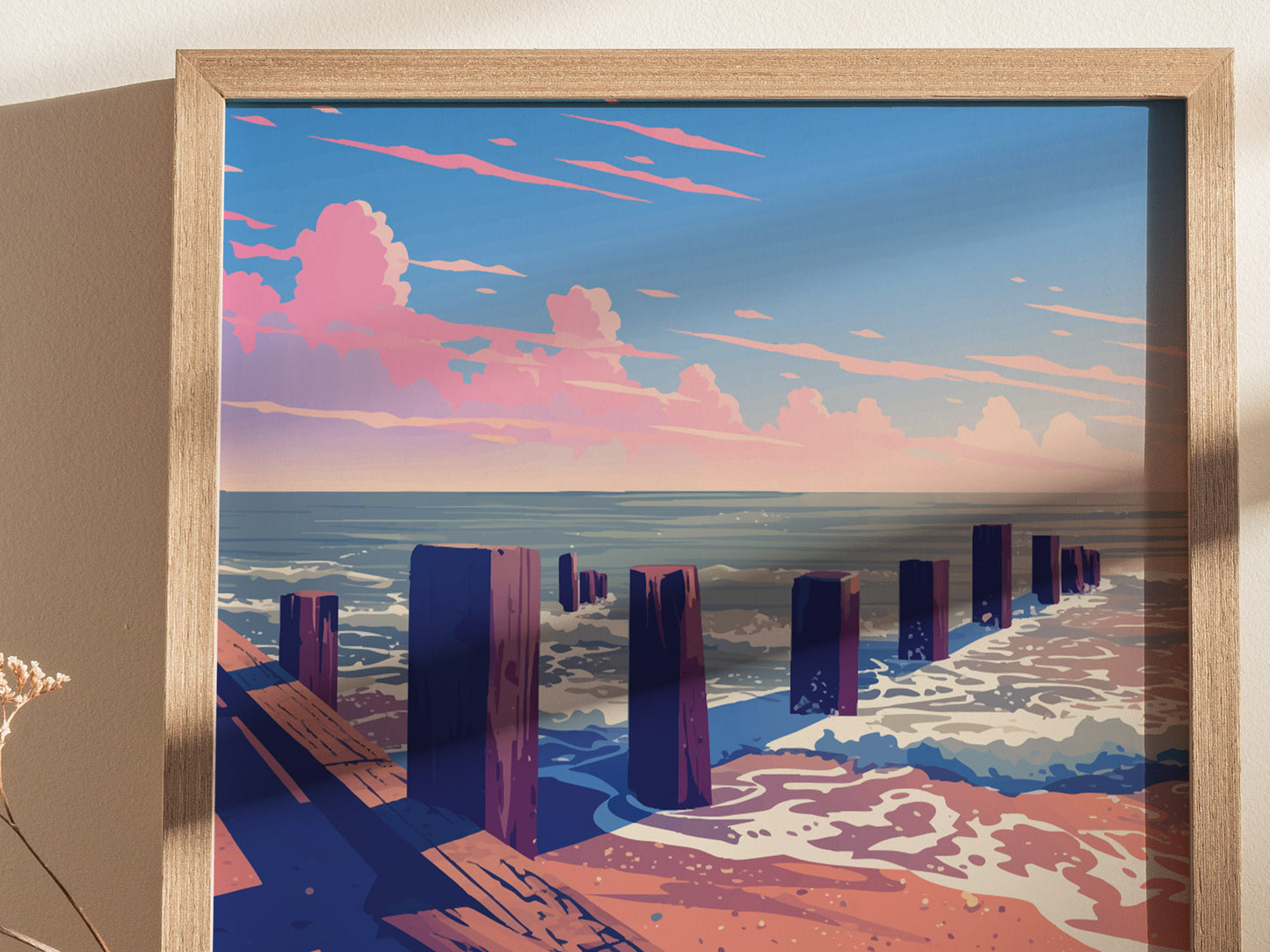 A framed artwork depicting a coastal scene with wooden posts in the sand, waves crashing, and a vibrant sunset sky with pink clouds over the ocean.