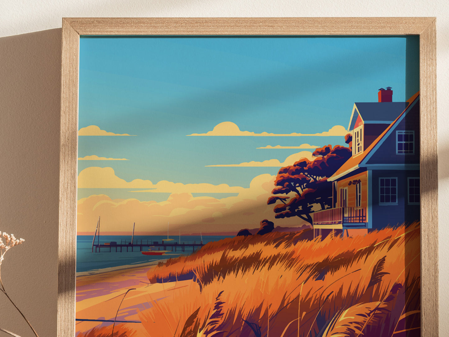 A framed poster depicts a coastal scene with a house, vibrant orange grasses, and a distant pier under a blue sky with clouds. Warm tones create a serene, artistic ambiance.