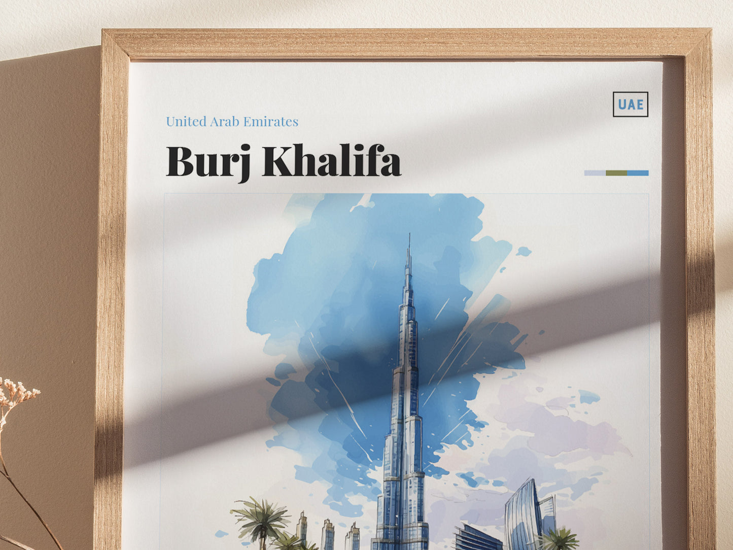Framed poster featuring a watercolor illustration of the Burj Khalifa with a blue sky background. Text reads United Arab Emirates, Burj Khalifa. Shadows and dried flowers are visible.