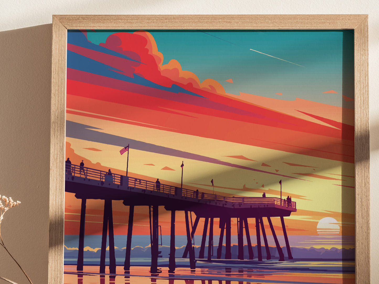 A framed artwork depicts a vibrant sunset over a pier, with silhouetted figures and colorful clouds in shades of orange, pink, and blue, reflecting on calm water.