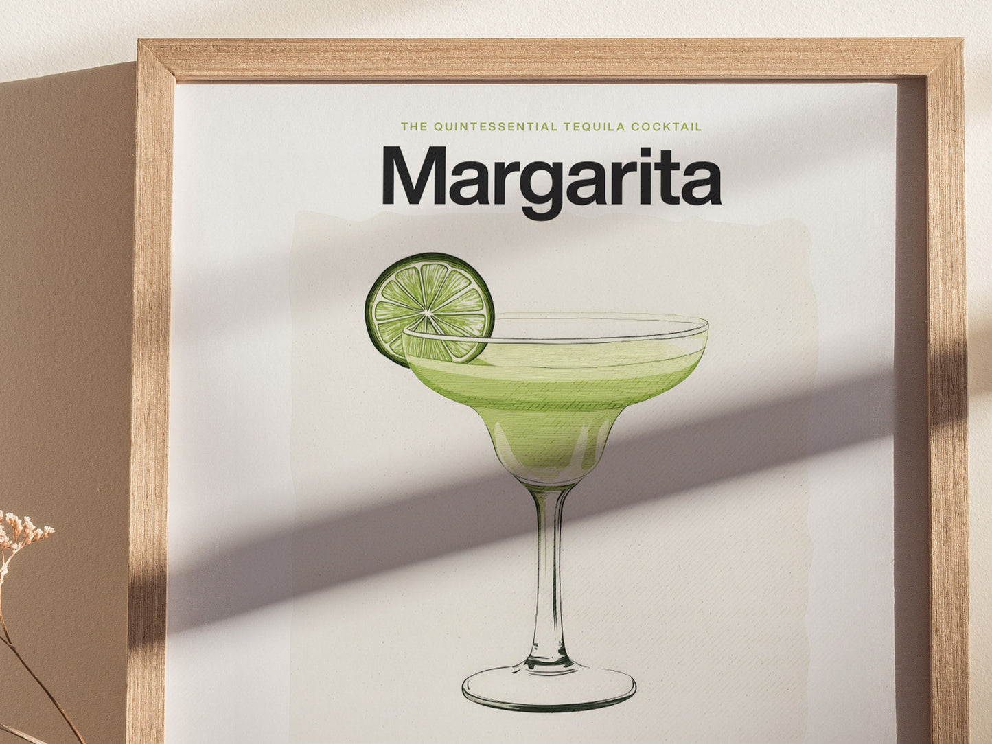 A framed poster features a Margarita cocktail illustration with a lime garnish, set against a neutral wall. Sunlight casts gentle shadows.