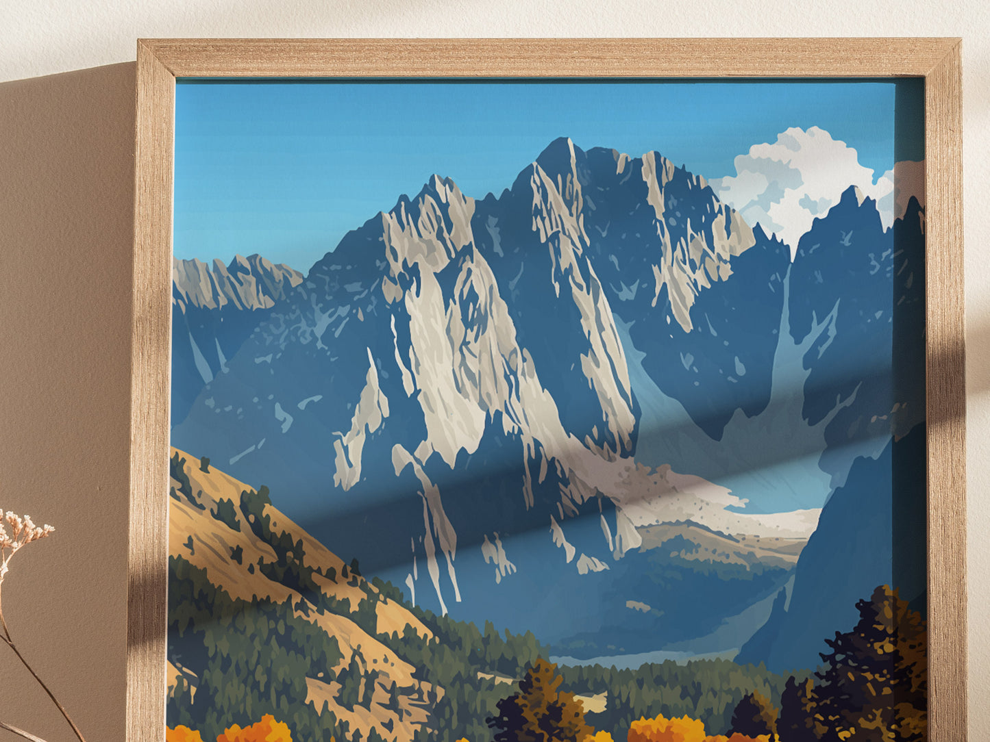 A framed poster depicts a stylized view of rugged mountains under a blue sky, with autumn-colored trees in the foreground, creating a dramatic landscape scene.