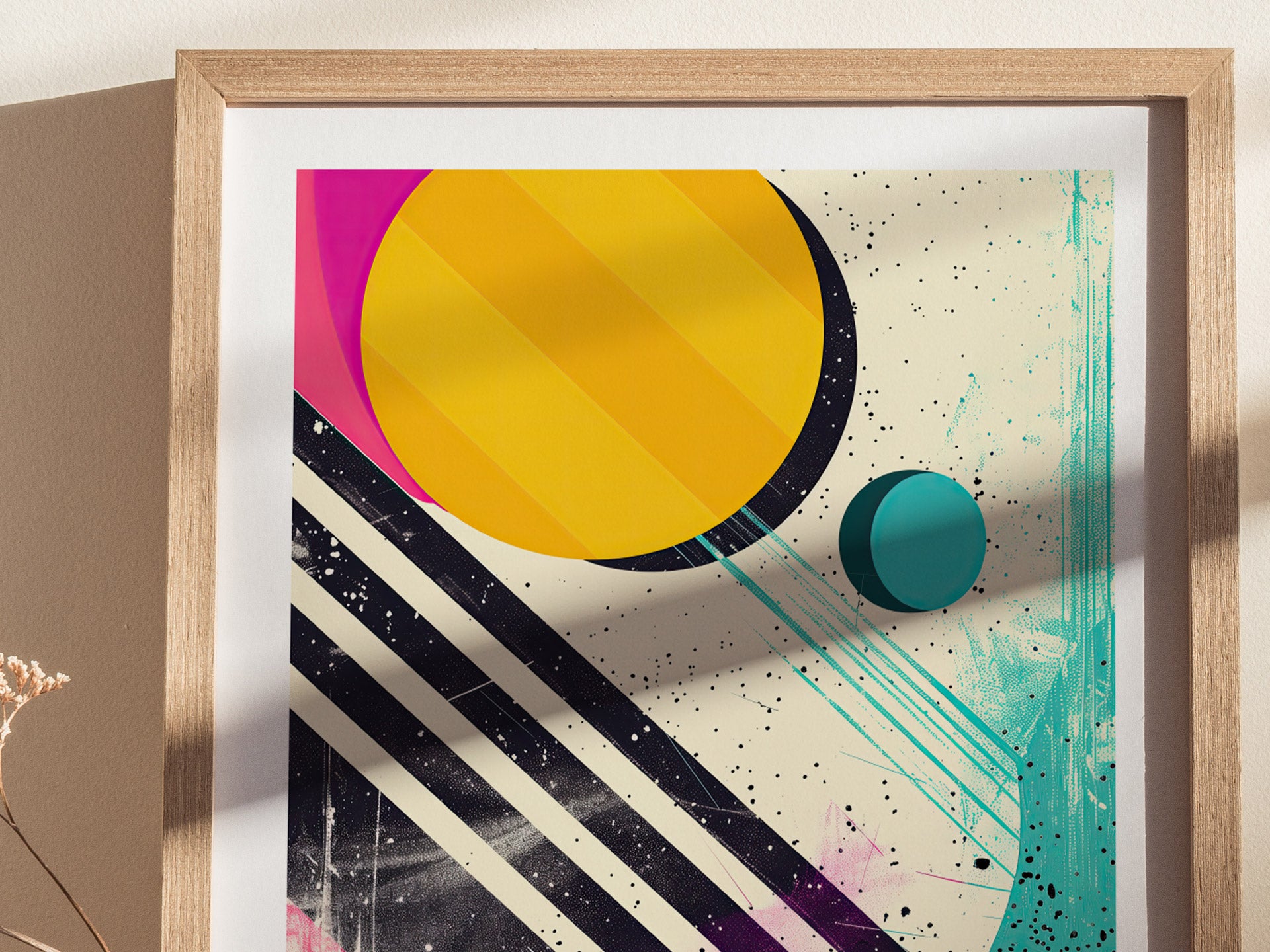A framed poster features bold abstract shapes with a large yellow circle, a smaller blue circle, and black diagonal stripes on a speckled background. Bright colors evoke 1980s retro style.