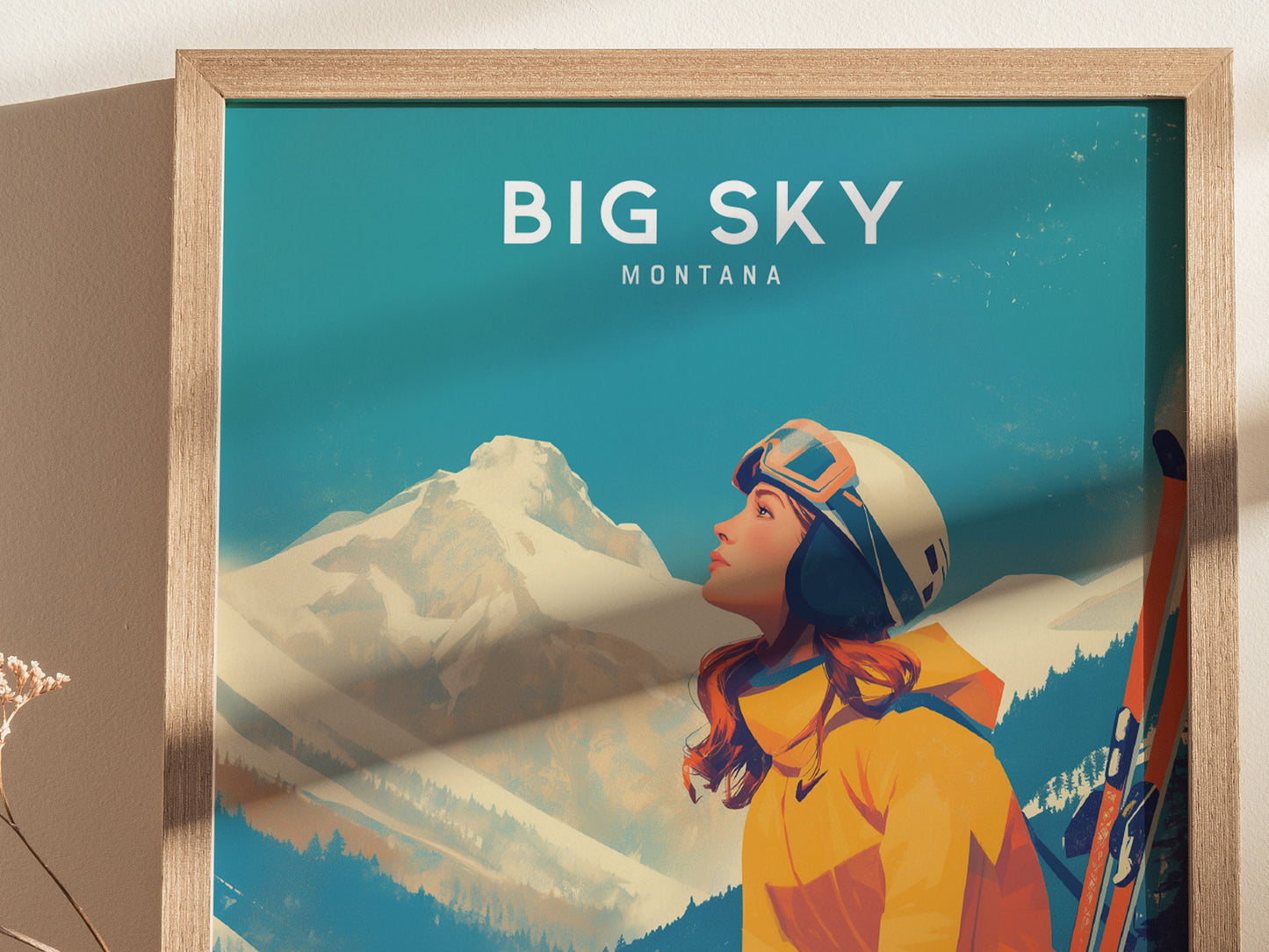 A framed poster features a woman in a yellow jacket and helmet looking up at a snowy mountain peak. The text reads Big Sky Montana.