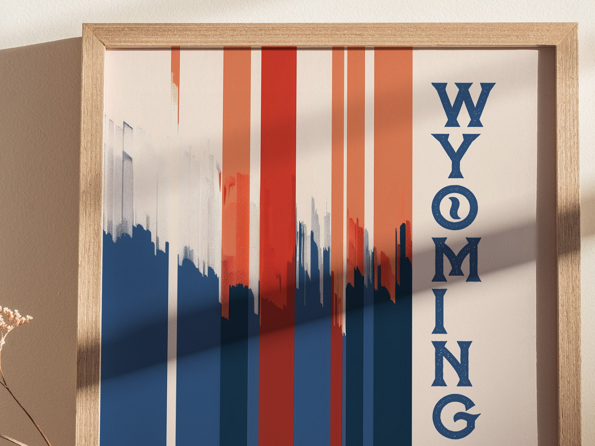 Framed Wyoming poster with vertical red, white, and blue geometric stripes and WYOMING written vertically in bold blue text. The minimalist design features abstract brush strokes.