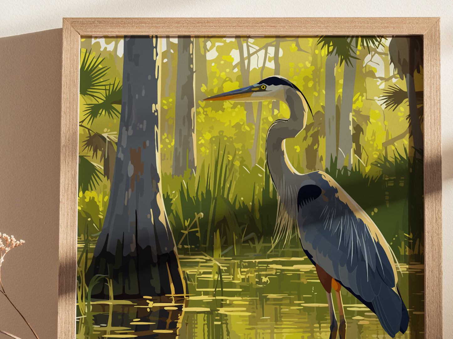 A framed art print depicts a Great Blue Heron standing in a lush, sunlit swamp with cypress trees and sawgrass. The serene scene highlights the vibrant colors of the Everglades.