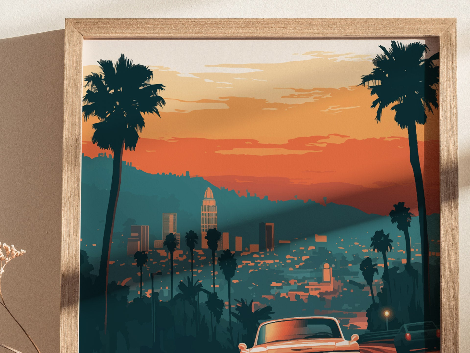 A framed poster depicts a stylized Los Angeles cityscape at sunset, featuring palm trees, city buildings, and a vintage car in the foreground under a vibrant orange sky.