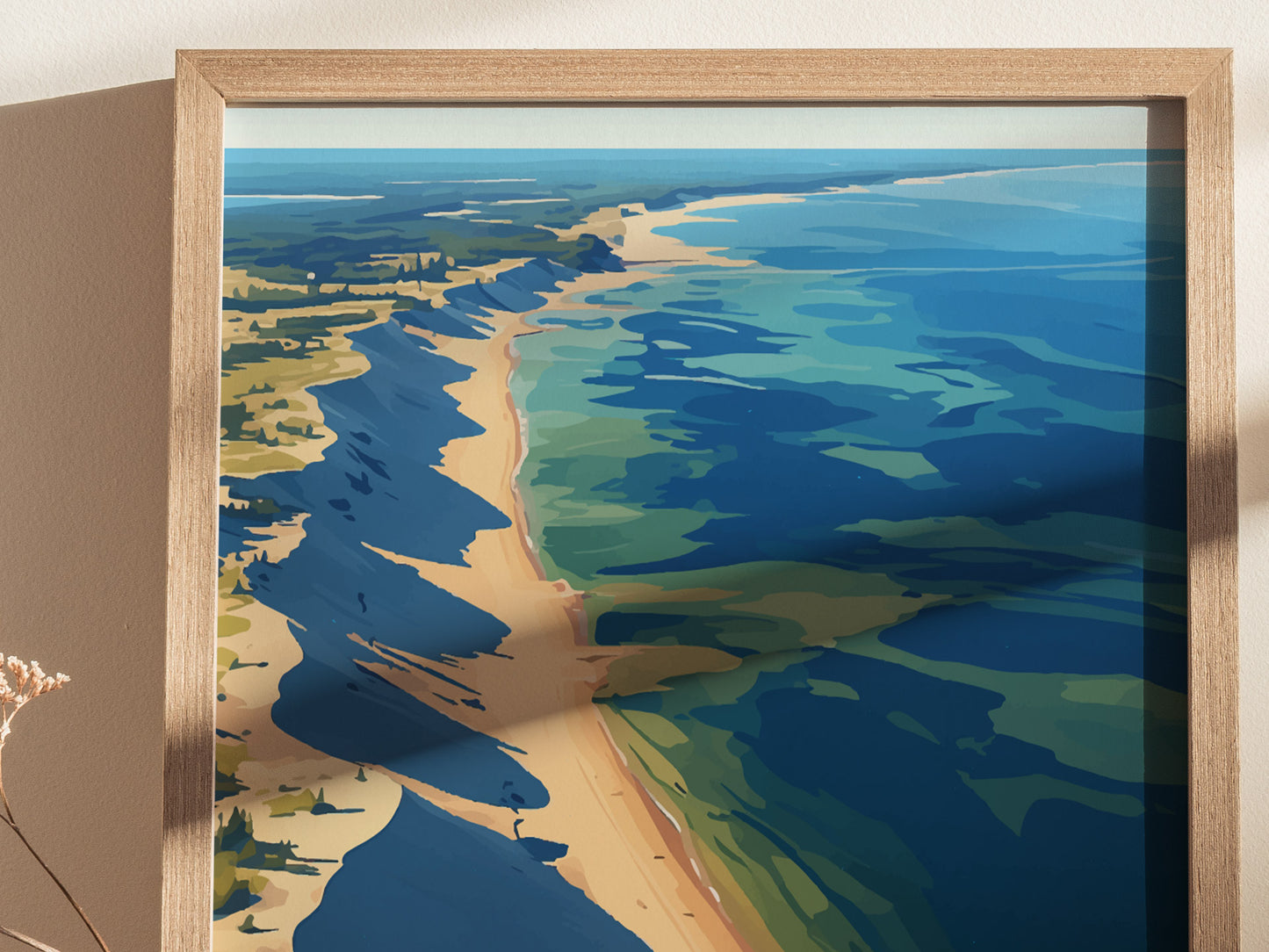 A framed poster depicts an abstract aerial view of a coastline with sandy beaches, blue water, and green land. It casts a shadow on a beige wall.
