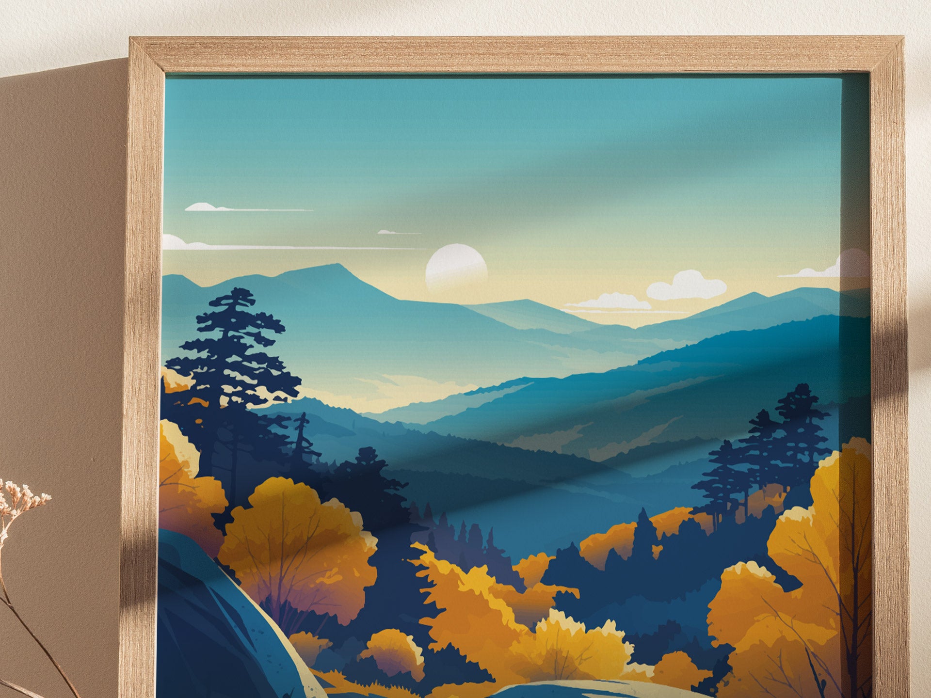 A framed poster depicts a serene mountain landscape with layered ridgelines and a setting sun. The scene includes silhouettes of trees and vibrant autumn foliage under a blue sky with scattered clouds.