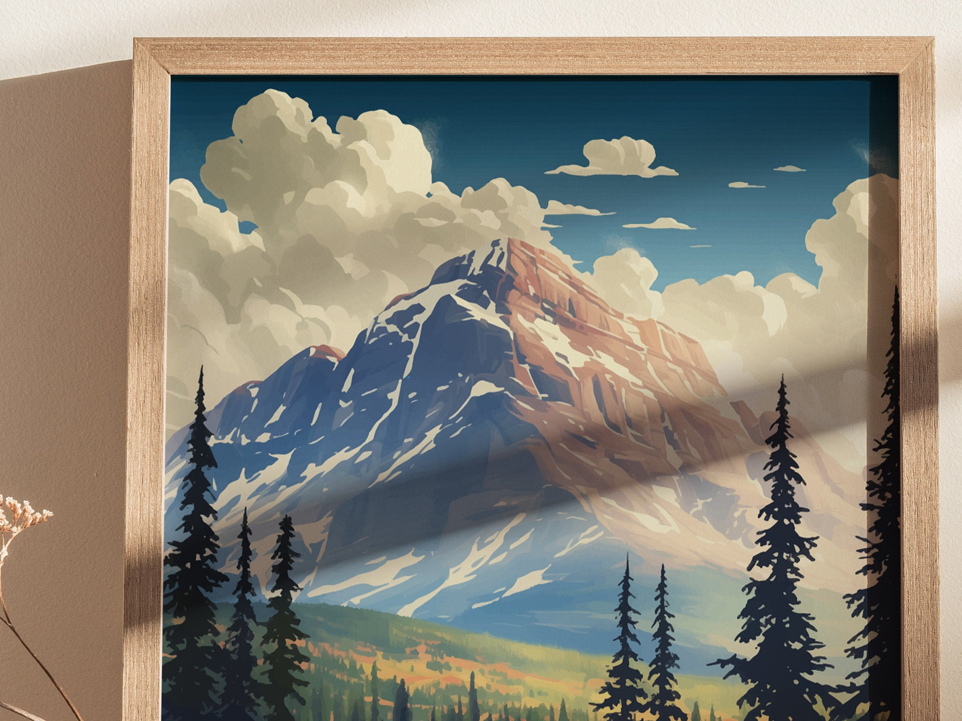 Framed artwork depicting a majestic mountain peak under a blue sky with fluffy clouds, surrounded by evergreen trees. The scene captures a serene, natural landscape.