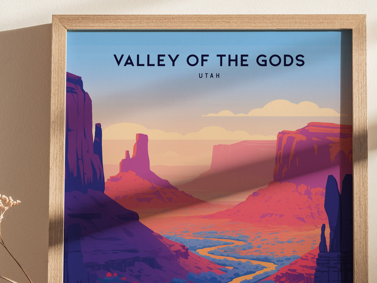 A framed poster titled Valley of the Gods, Utah features a stylized landscape with vibrant red rock formations and a winding river under a pastel sky.