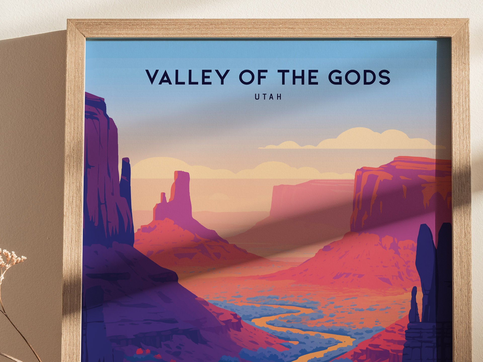 A framed poster titled Valley of the Gods, Utah features a stylized landscape with vibrant red rock formations and a winding river under a pastel sky.