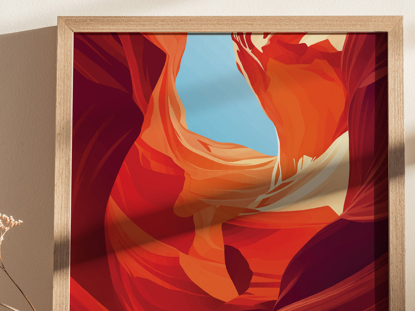 A framed poster featuring abstract, vibrant orange and red sandstone formations with a bright blue sky, reminiscent of Antelope Canyon. The wooden frame casts a soft shadow on the wall.