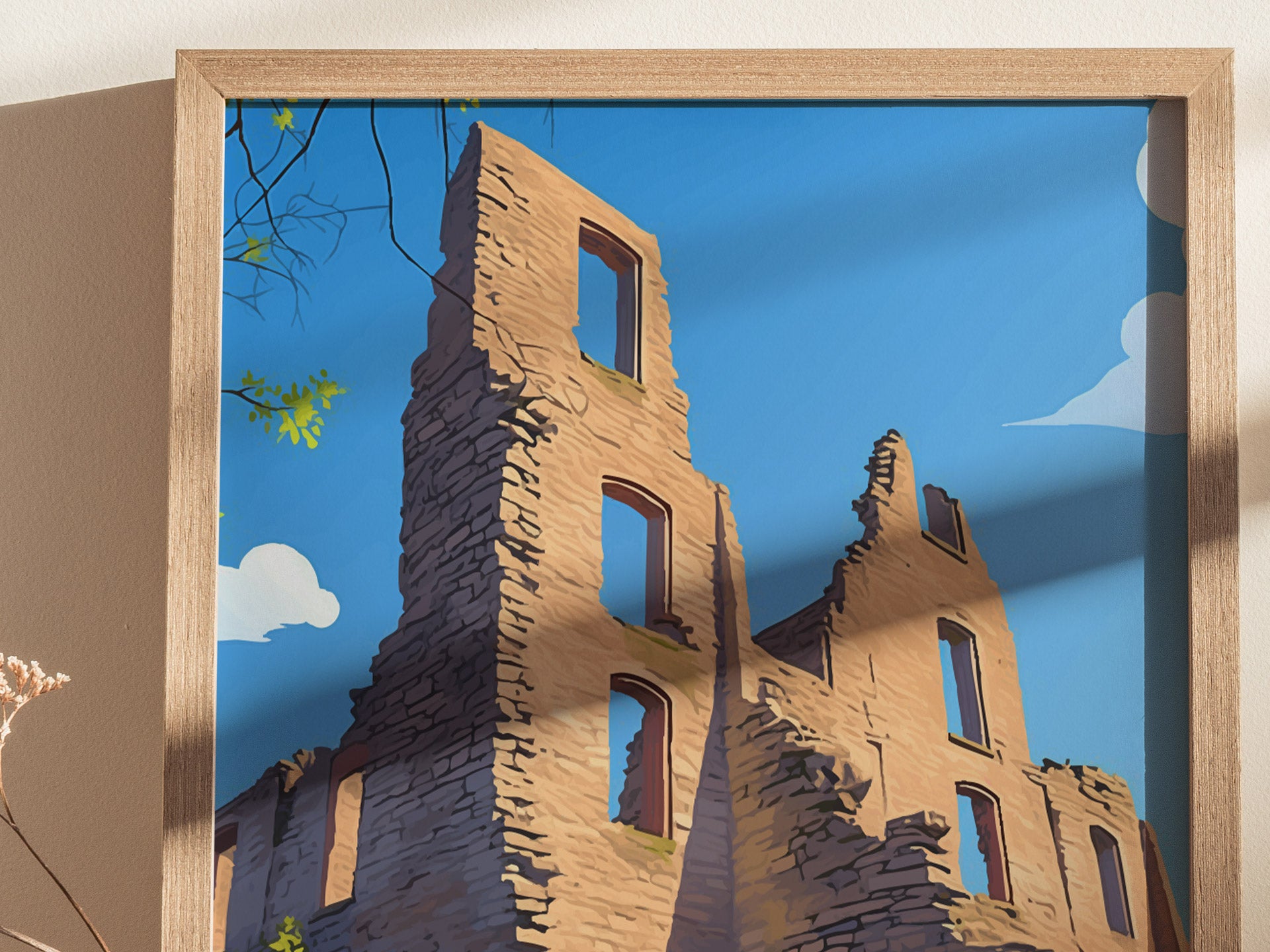 A framed artwork depicts the ruins of a stone building against a clear blue sky. Sunlight casts shadows, and some green leaves are visible in the top left corner.