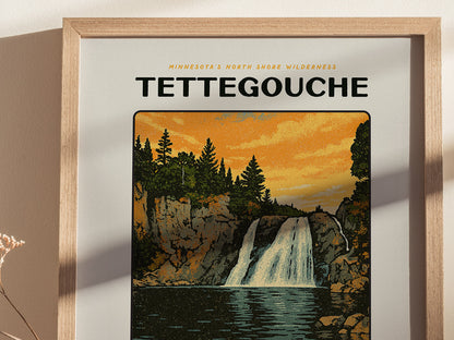 A framed poster depicts a waterfall cascading between rocky cliffs under a vibrant orange sky, with pine trees lining the top. The text reads Minnesotas North Shore Wilderness Tettegouche.