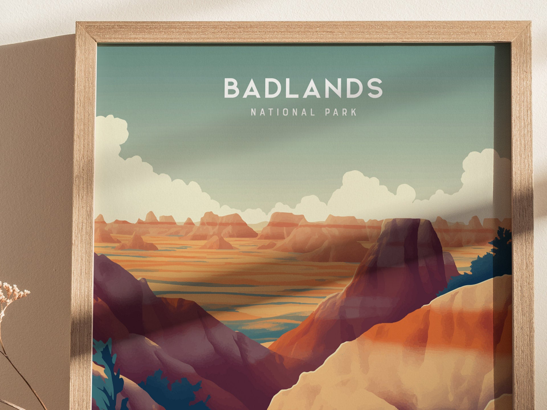 Illustrated poster of Badlands National Park features vibrant layers of orange and purple buttes under a blue sky with clouds, framed in light wood.