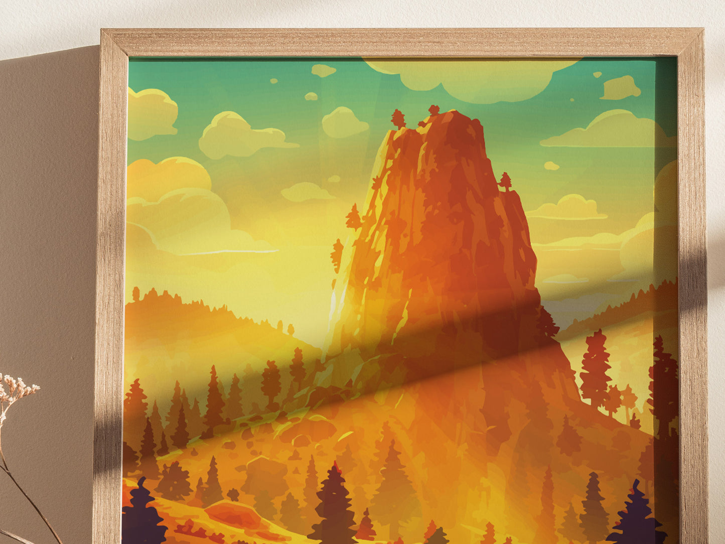 A framed poster depicts a stylized, vibrant landscape of a towering granite rock surrounded by pine trees under a sky with fluffy clouds, capturing a sunset glow.