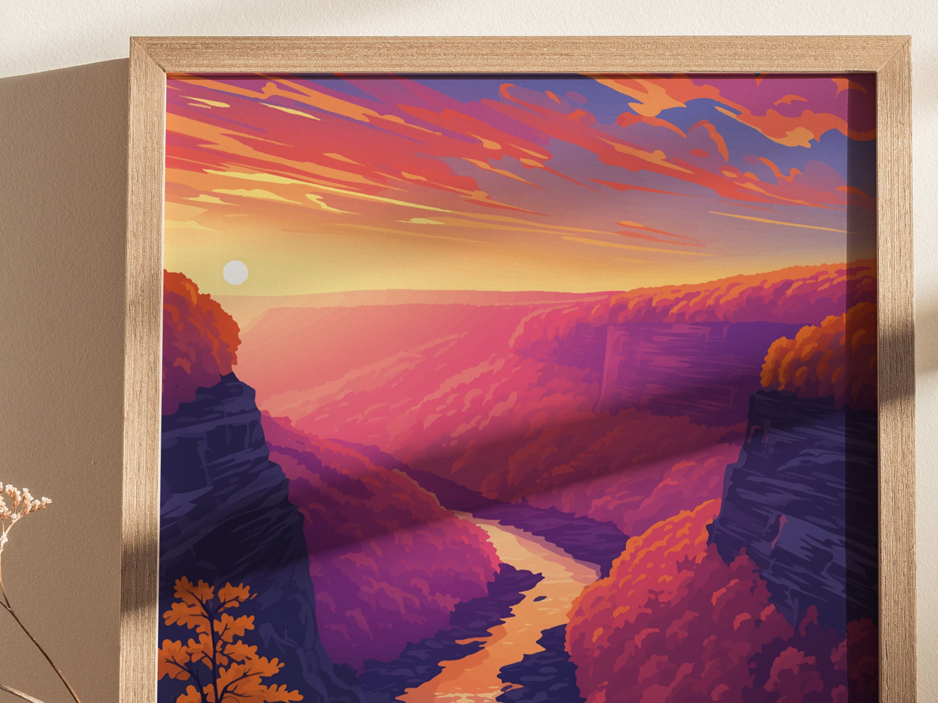 A framed poster depicting a vibrant sunset over a gorge, with a winding river and colorful, forested canyon walls in shades of pink, orange, and purple.