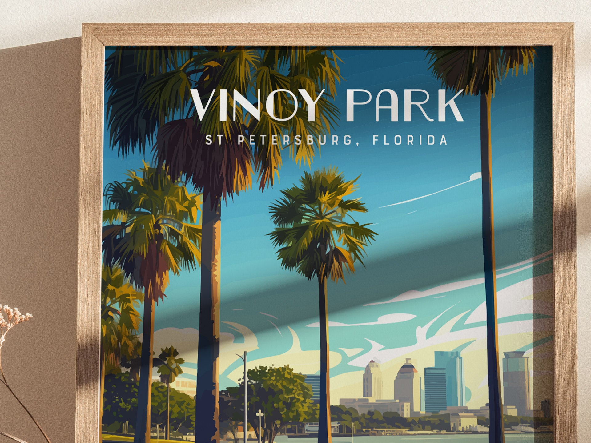 A framed poster of Vinoy Park in St. Petersburg, Florida, featuring tall palm trees against a blue sky and the citys skyline in the background.