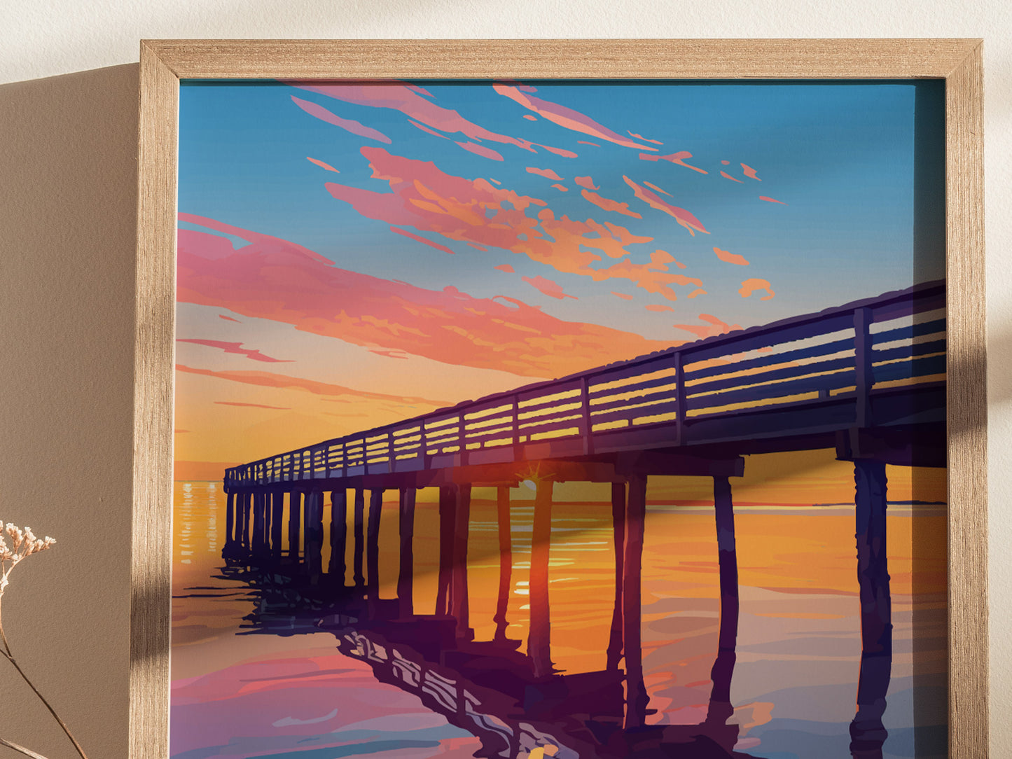 A framed poster depicting a vibrant sunset over a pier, with pink and orange clouds reflecting on the water, creating a serene coastal scene.
