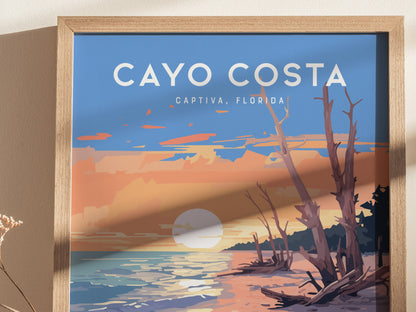 A framed poster depicts a vibrant sunset over a coastal landscape with driftwood and a calm sea, labeled Cayo Costa, Captiva, Florida.