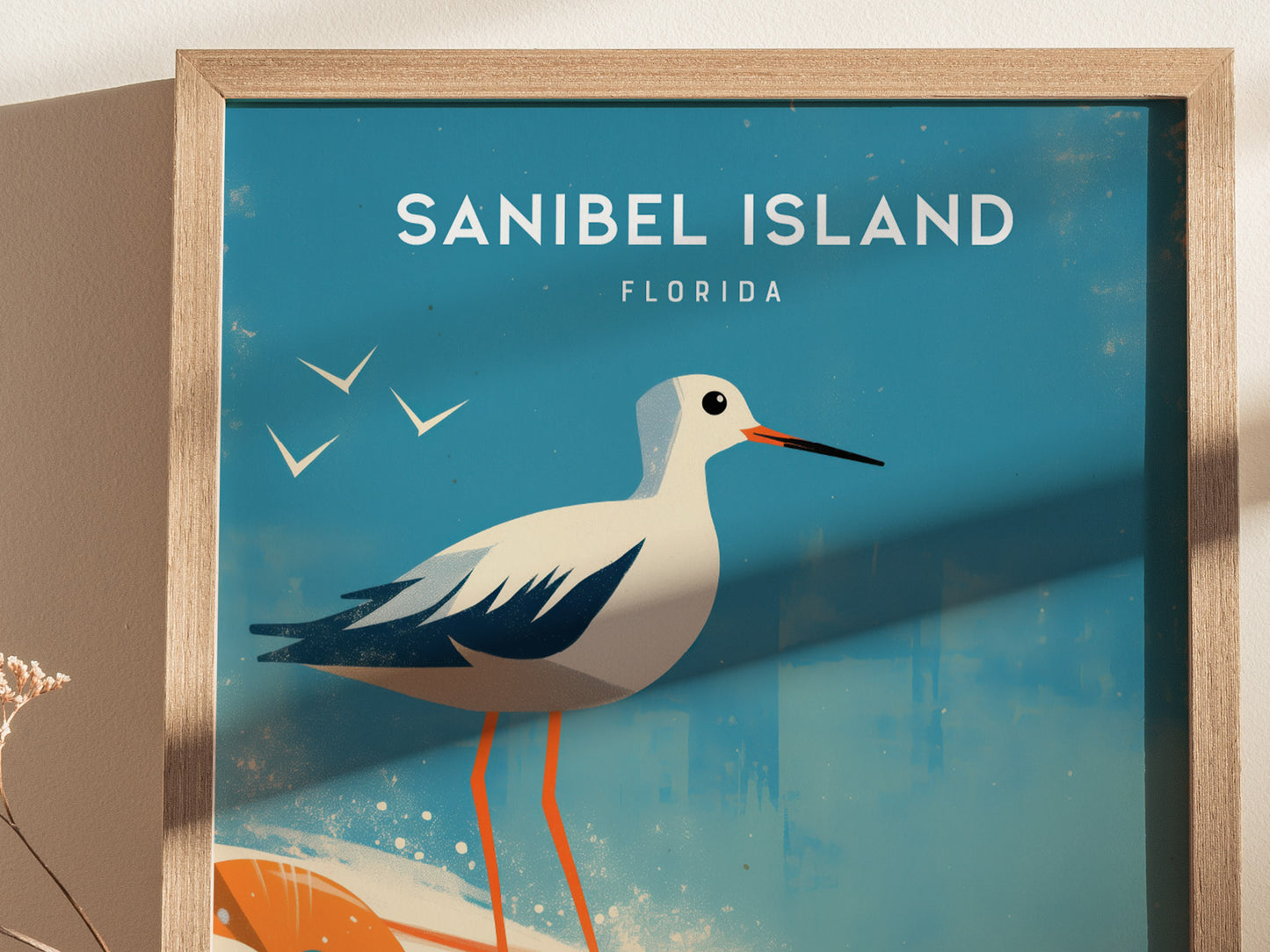 A framed poster features a stylized sandpiper against a blue background with the text Sanibel Island, Florida and silhouettes of birds in flight.