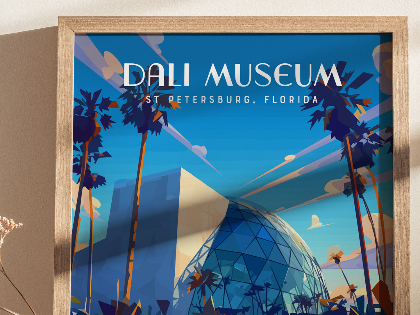 A framed poster of the Salvador Dali Museum depicts its iconic glass atrium and geometric structure, surrounded by tall palm trees under a bright blue sky in St. Petersburg, Florida.