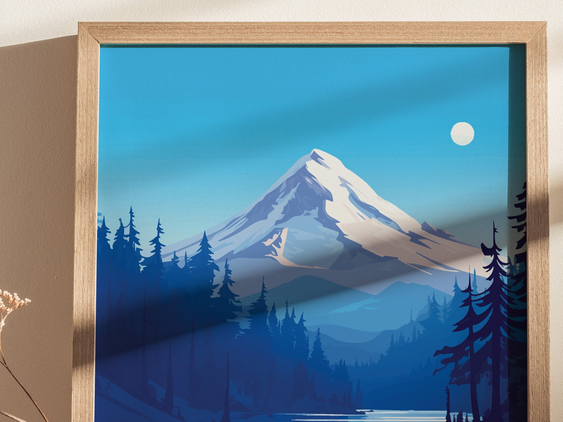 A framed artwork depicting a snow-capped mountain under a clear blue sky with a bright sun. Tall, dark evergreen trees line the foreground, creating a serene landscape.