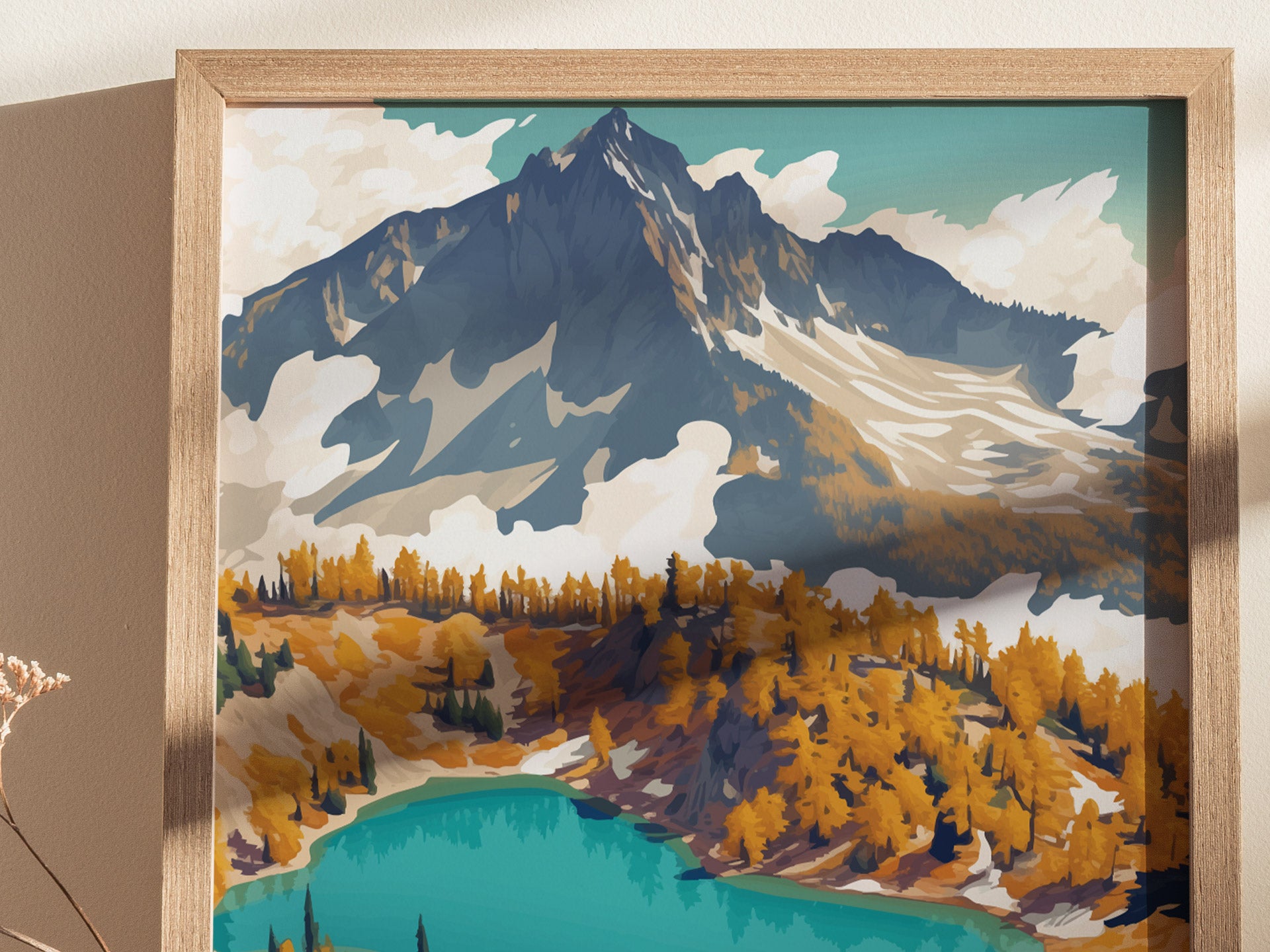 A framed poster depicts a vibrant mountain scene with a turquoise lake, golden trees, and rugged snow-capped peaks under a clear sky. The artwork captures a serene landscape.