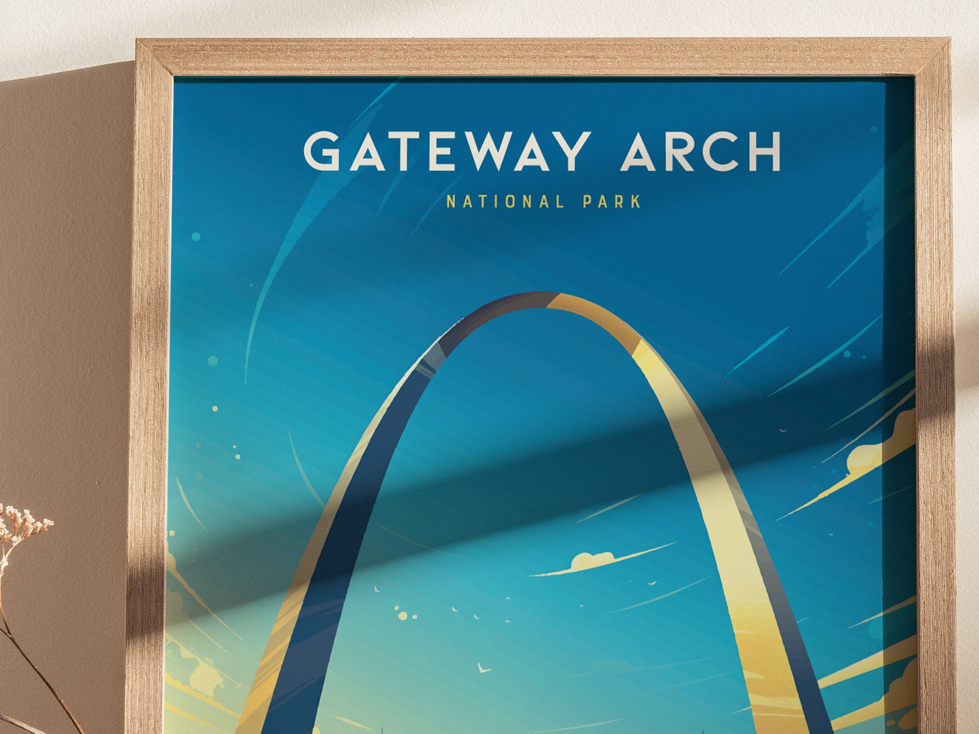 A framed poster of the Gateway Arch against a vibrant blue sky, with stylized clouds and light reflections. The text Gateway Arch National Park is prominently displayed at the top.