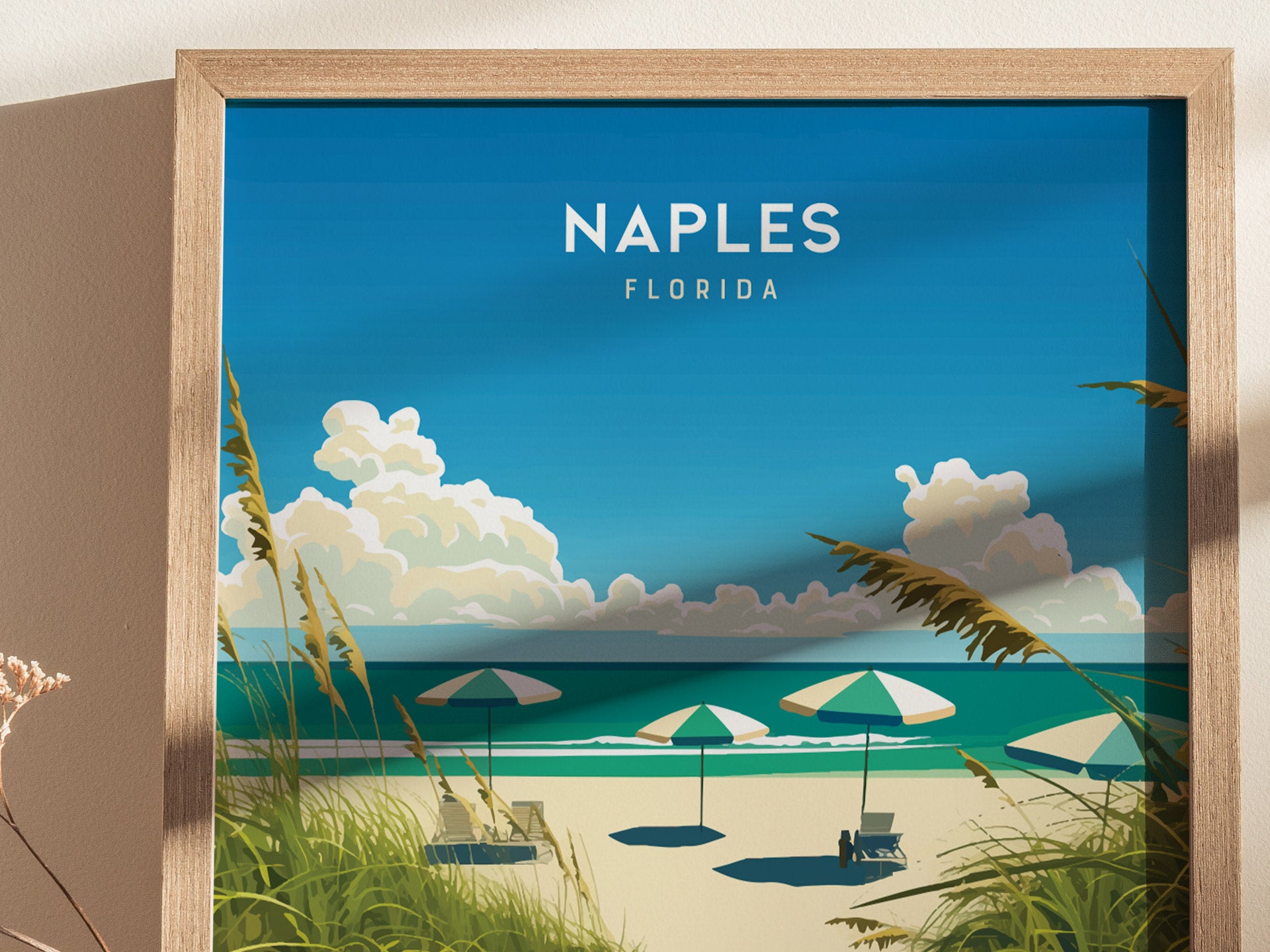 Framed artwork depicts a serene beach scene with green and white umbrellas, soft surf, and fluffy clouds against a bright blue sky, titled Naples Florida.