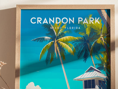 A framed poster of Crandon Park Beach, Miami, features vibrant illustrations of swaying coconut palms against a bright blue sky. The image captures a tropical vibe with a lifeguard tower partially visible at the bottom.